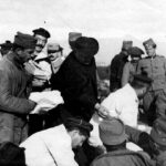 Монсињор Боло дели цигарете српским регрутима које превијају француски морнари